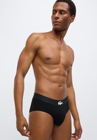 Zwarte slips met een effen ontwerp, voorzien van een zachte tailleband en een wit logo-accent. Gemaakt van stretchstof voor comfort.
