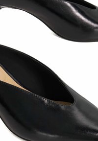 Black leather slip-on shoes with a smooth, shiny surface, featuring a wide cutout for the instep and a pointed toe design.