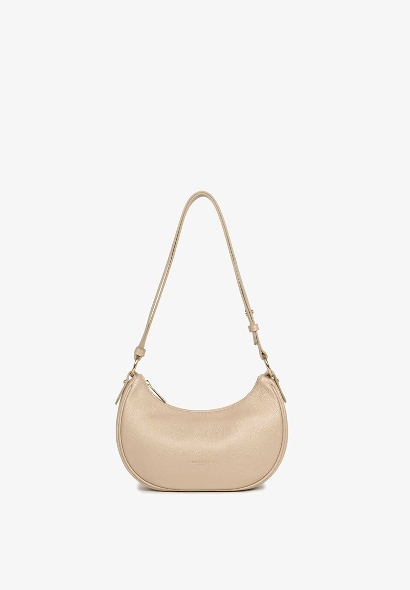 Petit sac à bandoulière en cuir beige avec forme arrondie, bandoulière réglable et fermeture éclair.