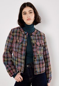 Giacchetto in tweed multicolore con taglio corto, collo rotondo e due tasche frontali. Presenta bottoni neri e un tessuto testurizzato.