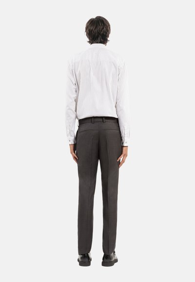 Wit en grijs gestreepte langesleeve shirt gecombineerd met donkergrijze op maat gemaakte broeken, met een rechte pasvorm en subtiel ruitenpatroon. Zwarte schoenen.