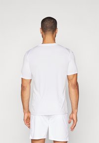 Hvid atletisk t-shirt med korte ærmer, lavet af glat, fugttransporterende stof. Har en rund halsudskæring og minimalistisk design.