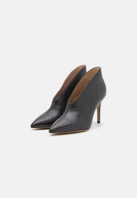 Black leather high-heeled shoes with pointed toes, a sleek silhouette, and a low-cut design showcasing the foot's arch.