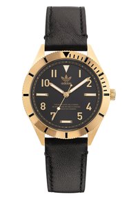 Montre dorée avec un cadran noir, grands index luminescents, bracelet en cuir noir et lunette crantée. Elle présente un logo Adidas.