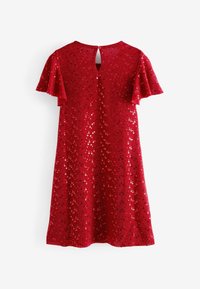 Robe rouge avec des manches courtes à volants, un dos en forme de clé, et recouverte de sequins circulaires pour la texture et l'éclat.