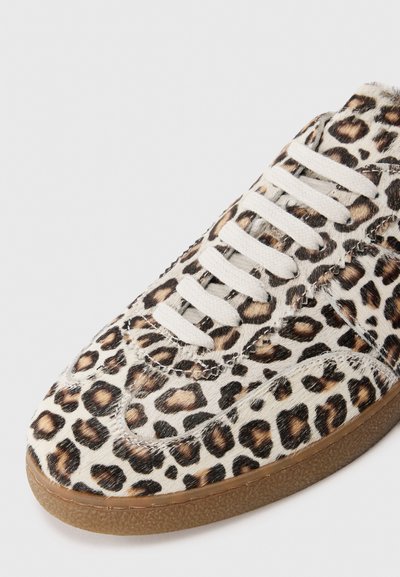 Sneakers med leopardmönster och en texturerad ovandel som liknar päls, vita snören och en beige gummisula. Har kontrasterande svarta och bruna mönster.