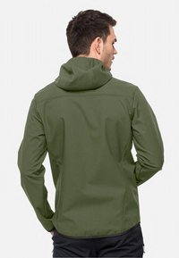 Veste à capuche verte avec une texture lisse, un design ajusté et une fermeture éclair. Elle présente des poignets élastiqués et un ourlet incurvé.