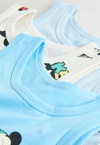 Trois débardeurs en coton superposés, comprenant un bleu clair, un blanc cassé avec des lettres colorées, et un bleu clair avec des accents de design noirs et rouges.