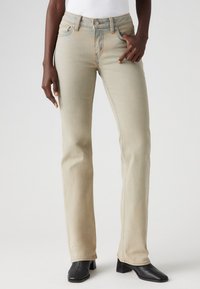 Jean droit beige en denim doux, avec un design classique à cinq poches, des détails de couture subtils et une taille mi-haute.