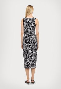 Midi haljina s leopard uzorkom u crno-bijeloj boji, tijelo je prilagođeno, bez rukava i od glatkog materijala. Pogled s leđa prikazuje minimalne šavove.