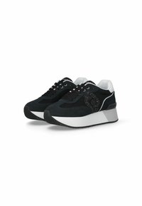 Zapatillas negras con materiales de malla y ante, que presentan un logo decorativo, acentos blancos y una suela gruesa con un diseño de goma texturizada.