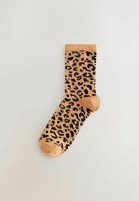 Beige sok met zwart luipaardprintpatroon; heeft een geribbelde boord, een gladde textuur en een afgeronde teen.