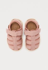 Rosa tygsandaler med öppen design, korsande bandmönster och texturerad sula. Kardborreband vid ankeln.