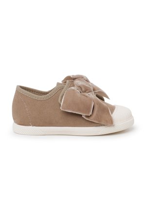 Zapatillas de ante beige para niños con puntera y suela de goma blanca, que presentan un gran lazo de tela suave en la parte superior.