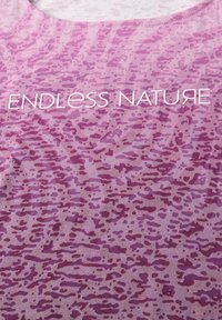 Lila textil med ett prickigt mönster i varierande nyanser av rosa. Texten lyder "ENDELS NATURE" i fet, vit stil.