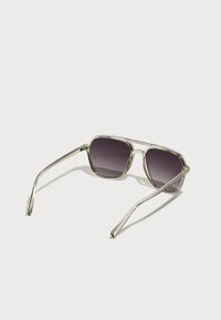 Occhiali da sole con montatura in metallo e lenti gradiente viola, design angolare e steli sottili, con accenti in plastica trasparente vicino alle lenti.