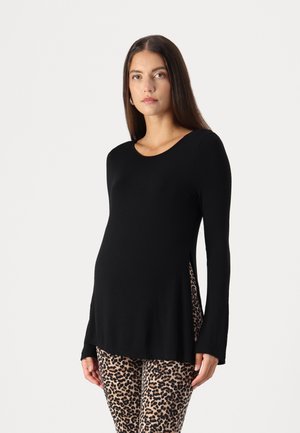 Zwarte lange mouw top met een ronde halslijn en zijsplits, gecombineerd met leggings met luipaardprint. Zacht materiaal, losse pasvorm, geschikt voor zwangerschapskleding.