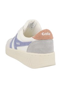 Bílé tenisky s semišovými fialovými a šedými akcenty, které mají texturovanou podrážku a hnědý opasek na patě s logem "Gola" v bílé barvě.