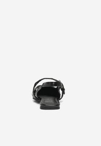 Sandalia negra de punta abierta con una textura de cuero suave, correa ajustable y acentos decorativos de metal. La suela plana mejora la comodidad.