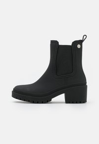 Botas de tobillo impermeables negras con paneles laterales elásticos, acabado texturizado, suelas de goma gruesas y tacón de bloque. Asa en la parte posterior para facilitar su uso.