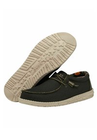 Scarpe slip-on nere in mesh con una tomaia testurizzata, suola di trazione beige maculata e dettagli di cucitura discreti. L'interno foderato presenta un motivo camouflage.