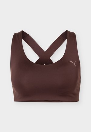 Καφέ αθλητικό σουτιέν με σταυρωτούς ιμάντες στην πλάτη και μικρό λογότυπο Puma στην αριστερή πλευρά, εμφανίζεται σε απλό λευκό φόντο.
