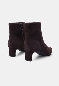 Botas de ante marrón hasta el tobillo con puntera redondeada, cremallera lateral y tacón cuadrado. Textura suave, diseño simple.