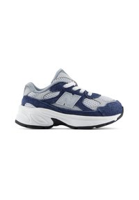 Baskets de sport gris et bleu marine avec lacets blancs, tige en mesh et daim, semelle blanche épaisse et logo latéral cousu sur fond blanc.
