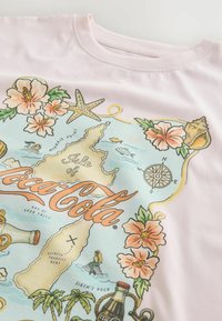 Dizajn s motívom mapy na bledo ružovej látke s kvetmi, morskými hviezdami, lastúrami, morskými pannami, kompasom a fľašami Coca-Cola.