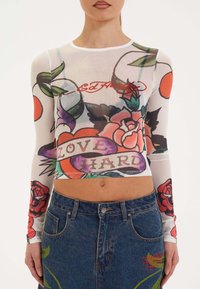 Doorzichtig wit lang mouw crop top met kleurrijke bloemenprints en de tekst "LOVE HARD" met een ronde hals en slim fit.