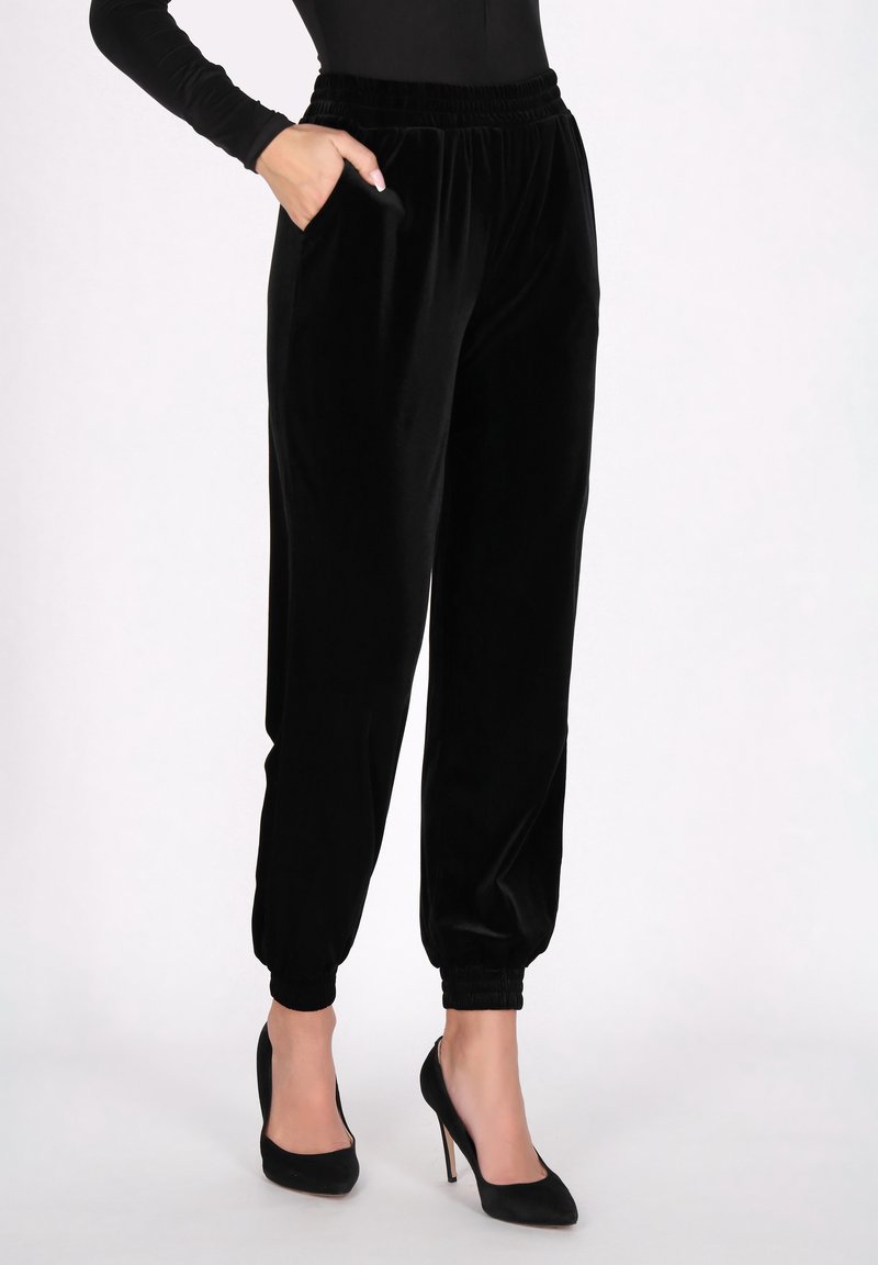 Zwarte fluwelen joggingbroeken met een elastische tailleband, zijzakken en opgerolde enkels. Soepele textuur, slim-fit en een veelzijdig ontwerp.