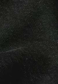 Tessuto di denim nero con una leggera brillantezza, caratterizzato da una texture liscia e una trama fitta. Variazioni sottili di colore e spessore sono visibili.