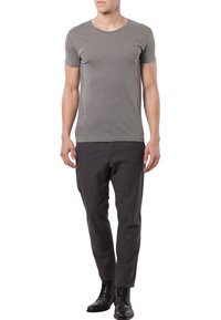 Grå T-shirt med korta ärmar i mjukt tyg, kombinerad med mörkgrå skräddarsydda byxor och svarta läderstövlar, som ger en figurnära silhuett.