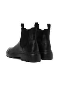 Par de botas Chelsea de cuero negro con suelas de goma gruesas y tiradores, mostradas desde un ángulo trasero sobre fondo blanco.