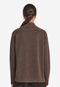 Brun stickad tröja med hög krage. Har en avslappnad passform, ribbad nederkant och slät yta. Enkel design, inga synliga mönster eller detaljer.