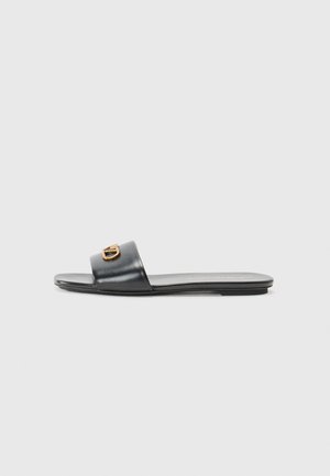 Sandalo piatto nero con una fascia larga, accento dorato e materiale in pelle liscia. Design minimalista con punta aperta e suola bassa.