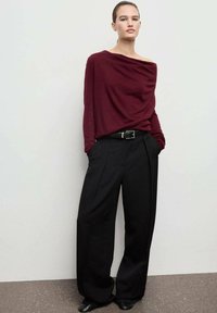 Burgundy off-the-shoulder top with draped detail, paired with high-waisted black wide-leg trousers. Smooth texture, minimalistic design.