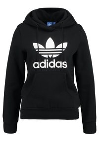 Svart Adidas-hoodie med en framficka, dragsko på huvan och en stor vit logotyp med tre ränder ovanför varumärket. Mjukt material.
