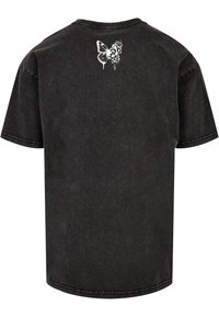 Camiseta de algodón negra de manga corta y cuello redondo. Presenta un diseño de mariposa blanca y flores impreso en la parte superior de la espalda.