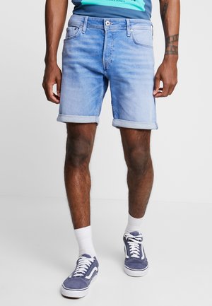 Shorts de denim azul claro con los dobladillos enrollados, con cinco bolsillos y cierre de botón. Combinados con zapatillas náuticas y calcetines blancos.