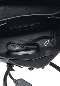 Czarna, usystematyzowana torebka na ramię z gładkiej skóry, z zamykaną na zamek kieszonką, odpinanym paskiem i wnętrzem z wieloma przegrodami.