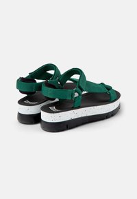 Gröna sandaler med remmar, en vit fläckig mellansula och svart yttersula. Har justerbara remmar och en texturerad fotbädd.