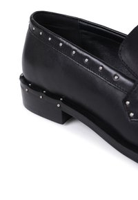 Black leather shoe with a low block heel, adorned with metal studs along the upper and sole edges for added detail and texture.