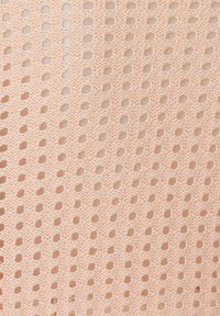 Hellpfirsichfarbener gestrickter Stoff mit einem offenen, kreisförmigen Muster und verschiedenen Lochgrößen, das ein strukturiertes, atmungsaktives Erscheinungsbild erzeugt.