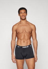 Sorte Nike boxer shorts med en kontrasterende hvid logo-linning, lavet af strækbart materiale, tætsiddende design, der tilbyder komfort og støtte.