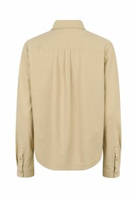 Bež dolgo rokavno srajco s ovratnikom z gumbi, zadaj ima dodatno gubo in gumbi na manšetah. Gladek material z enostavno teksturo.