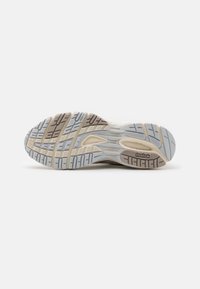 Reebok athletic shoe sole, featuring a textured pattern in light gray, beige, and brown. The design includes grooves for traction and support.