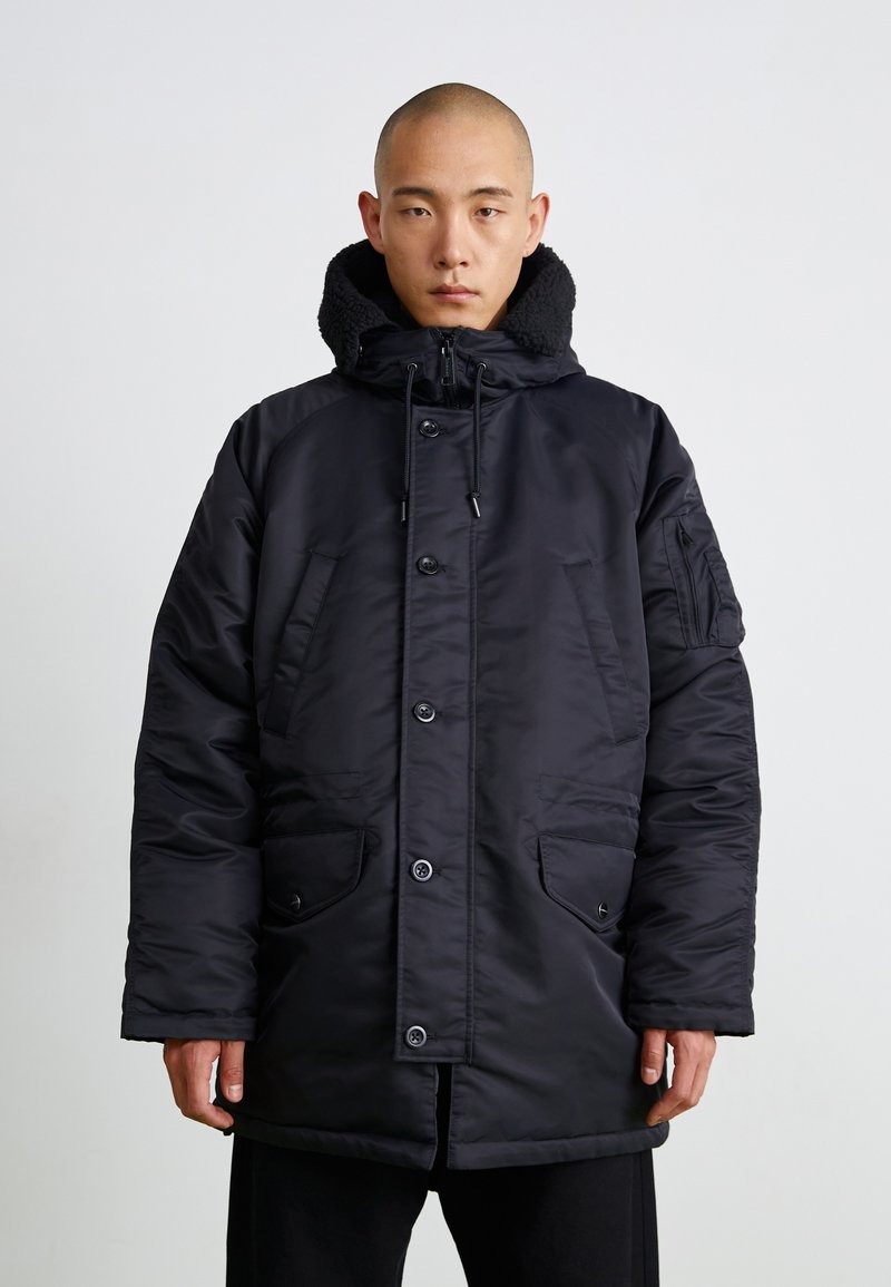 Schwarze gepolsterte Parka mit Kapuze, ausgestattet mit Druckknöpfen, zwei Fronttaschen und einem strukturierten Kragen. Hergestellt aus glattem, isoliertem Stoff.