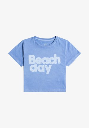 Camiseta de algodón azul claro con mangas cortas y cuello redondeado. Presenta el texto "Día de playa" en grandes letras blancas en el frente.