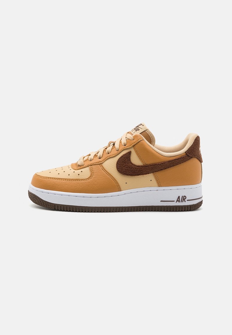 Baskets Nike Air Force 1 beige et marron avec tige en cuir, swoosh texturé, semelle intermédiaire blanche et semelle extérieure en caoutchouc marron.